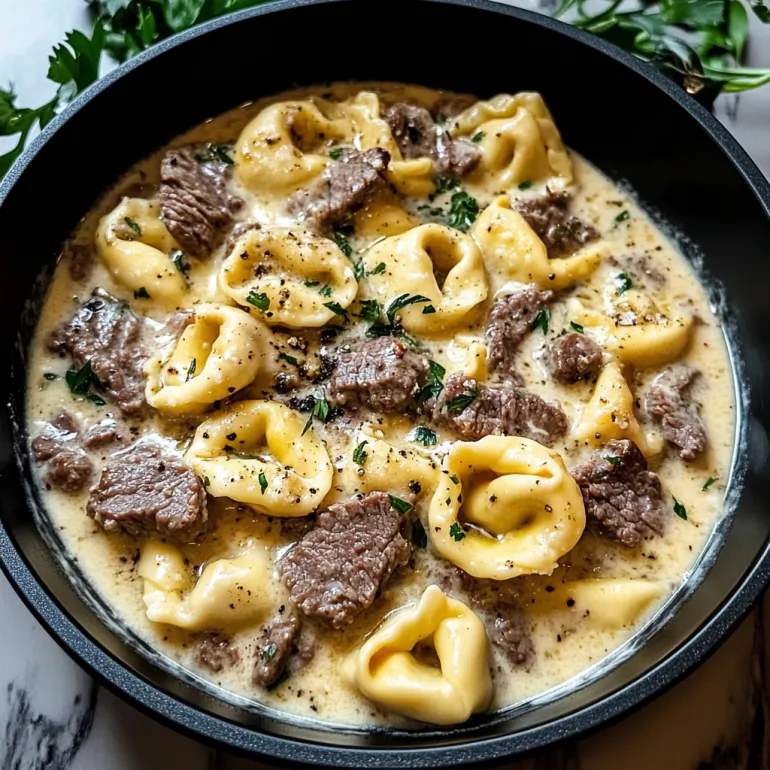 A bowl of cheesesteak tortellini in creamy provolone sauce.