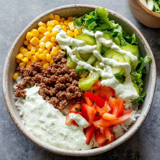 Un bol cu orez, vita tocata, rosii si salata verde.