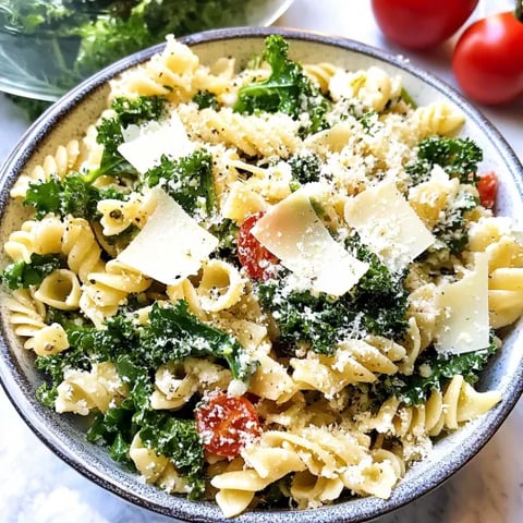 A bowl of pasta salad with kale and cheese.