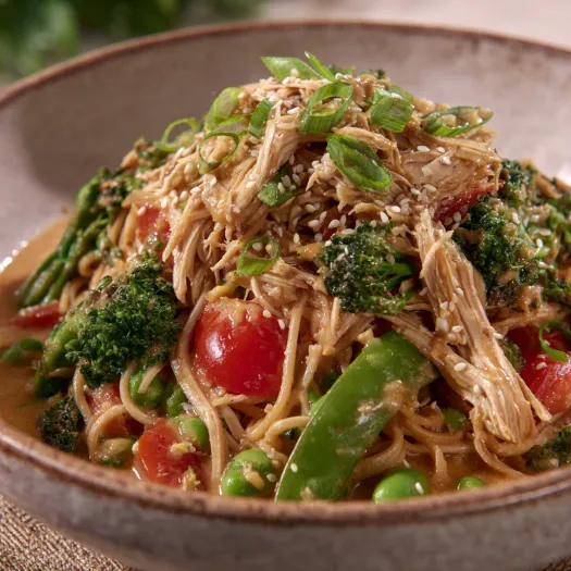 A bowl of peanut noodles with chicken.